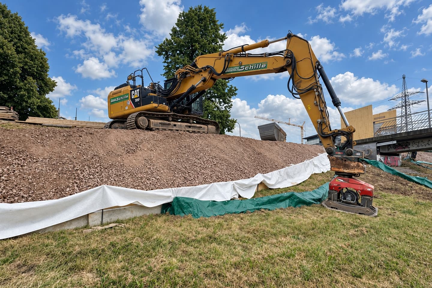 Schille-Bagger beim Dammbau mit Schotter und Geotextil in Offenburg